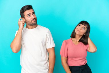 Genç çift mavi arka planda izole edilmiş kafalarını kaşırken bir fikir düşünüyorlar.