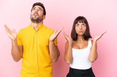 Pembe arka planda izole edilmiş genç çift kötü bir durum yüzünden hayal kırıklığına uğradı.
