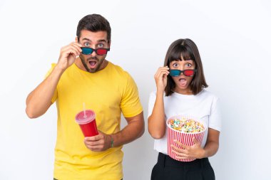 Beyaz arka planda yaşayan genç bir çift 3D gözlüklü ve elinde patlamış mısırla şaşırdı.