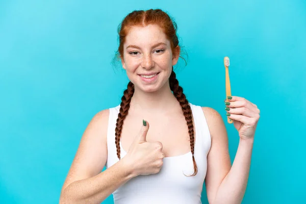 Young Caucasian Reddish Woman Brushing Teeth Isolated Blue Background Thumbs — Zdjęcie stockowe