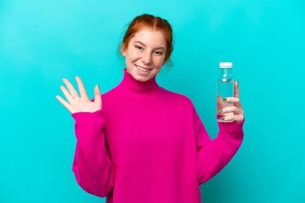 Young Caucasian Reddish Woman Bottle Water Isolated Blue Background Saluting — Fotografia de Stock