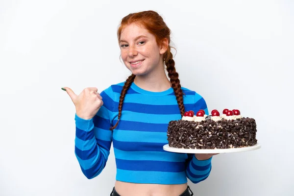 Młoda Rudawa Kobieta Trzyma Tort Urodzinowy Odizolowany Białym Tle Wskazując — Zdjęcie stockowe