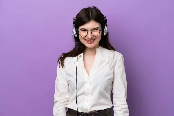 Telemarketer Russian woman working with a headset isolated on purple background with glasses and happy