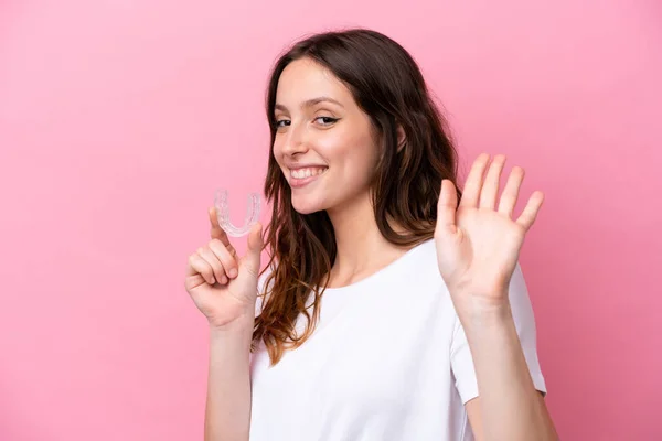 Young Caucasian Woman Holding Invisible Braces Isolated Pink Background Saluting — Stock fotografie