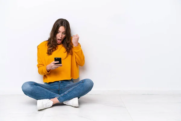 Mujer Joven Caucásica Sentada Suelo Aislada Pared Blanca Sorprendida Enviando — Foto de Stock