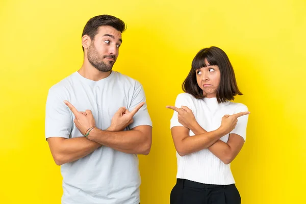 Young Couple Isolated Yellow Background Pointing Laterals Having Doubts — 图库照片