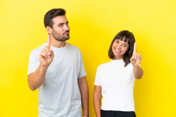 Junges Paar Isoliert Auf Gelbem Hintergrund Zeigt Und Hebt Einen — Stockfoto