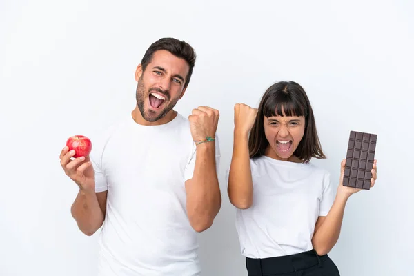 Young Couple Holding Chocolate Apple Isolated White Background Celebrating Victory —  Fotos de Stock