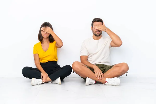 Casal Jovem Sentado Chão Isolado Fundo Branco Cobrindo Olhos Por — Fotografia de Stock