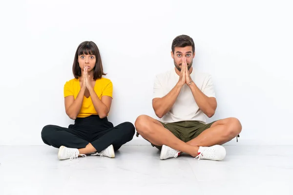 Young Couple Sitting Floor Isolated White Background Keeps Palm Together — 图库照片