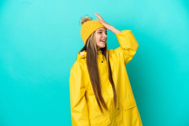 İzole edilmiş mavi arka plan üzerine yağmur geçirmez bir ceket giyen küçük kız bir şeyin farkına vardı ve çözümü amaçladı.