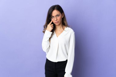 Mor arka planda izole edilmiş genç beyaz kadın bir şey gösteriyor.