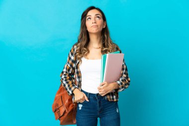 Genç bir bayan öğrenci mavi arka planda izole edilmiş ve araştırılıyor.