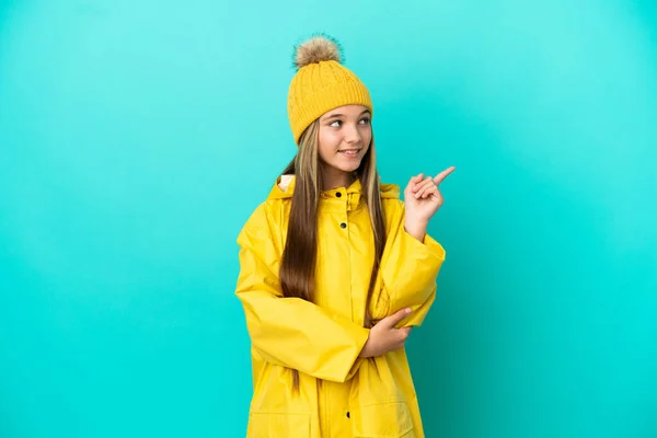 Menina Vestindo Casaco Prova Chuva Sobre Fundo Azul Isolado Apontando — Fotografia de Stock