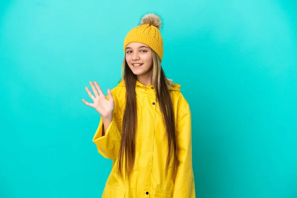 Little Girl Wearing Rainproof Coat Isolated Blue Background Saluting Hand — 스톡 사진