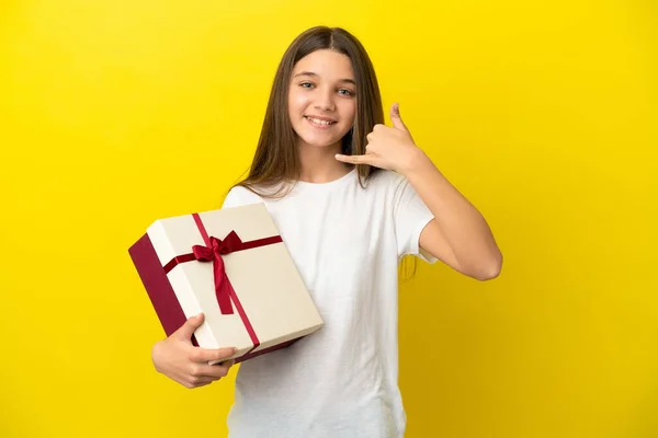 Little Girl Holding Gift Isolated Yellow Background Making Phone Gesture —  Fotos de Stock