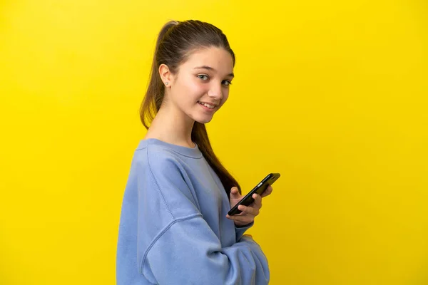 Little Girl Isolated Yellow Background Holding Mobile Phone Arms Crossed — Foto Stock