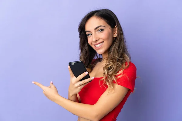 Young Caucasian Woman Isolated Purple Background Using Mobile Phone Pointing — Foto de Stock
