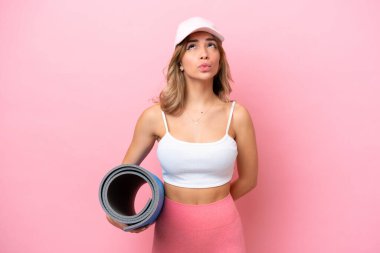 Genç sporcu kadın, elinde minderle yoga derslerine gidiyor.