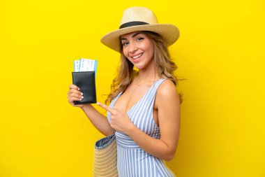 Genç bir kadın, sarı arka planda izole bir şekilde kumsala tatile gider ve onu işaret eder.