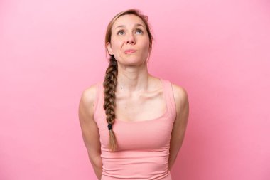 Genç beyaz kadın pembe arka planda izole edilmiş ve yukarı bakıyor.