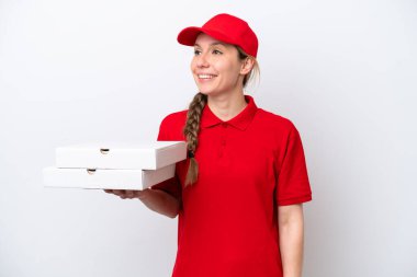 Pizza teslimatçısı kadın iş üniformalı beyaz arka planda izole edilmiş pizza kutuları alıyor ve gülümsüyor.