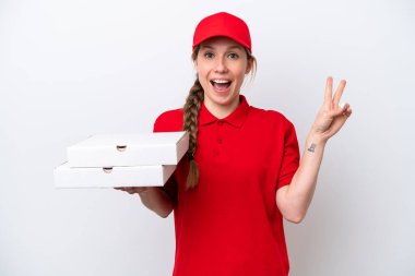 Pizza dağıtan kadın iş üniformalı beyaz arka planda izole edilmiş pizza kutuları alıyor gülümsüyor ve zafer işareti gösteriyor.