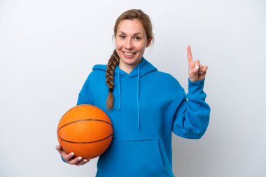 Beyazların arka planında izole edilmiş basketbol oynayan beyaz bir kadın en iyinin işareti olarak parmağını kaldırıyor.