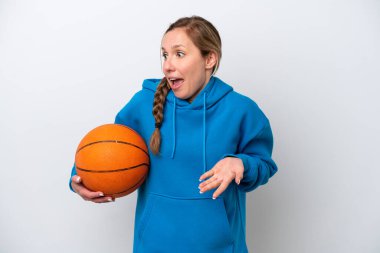 Beyaz arka planda basketbol oynayan beyaz tenli genç bir kadın sürpriz bir ifadeyle yan yana bakarken...