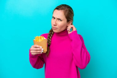 Kafkasyalı genç bir kadın elinde kızarmış cipslerle mavi arka planda kuşkuları var.