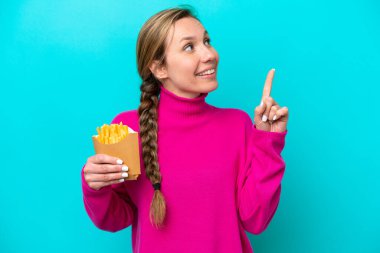 Elinde kızarmış cips tutan beyaz bir kadın mavi arka planda izole edilmiş. Harika bir fikre işaret ediyor.