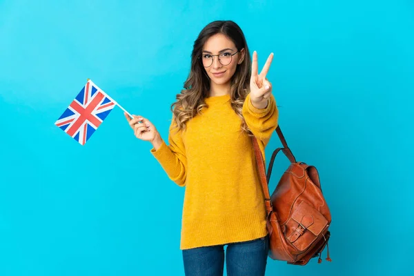 Молодая Латиноамериканка Флагом Великобритании Синем Фоне Улыбается Показывает Знак Победы — стоковое фото