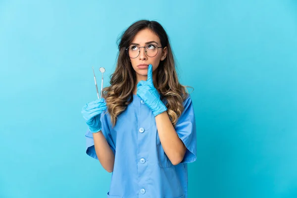 Woman Dentist Holding Tools Isolated Blue Background Having Doubts While — Stockfoto