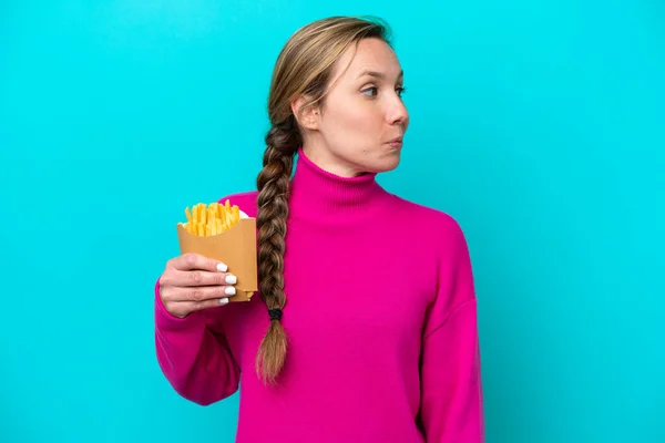 Young Caucasian Woman Holding Fried Chips Isolated Blue Background Looking — ストック写真