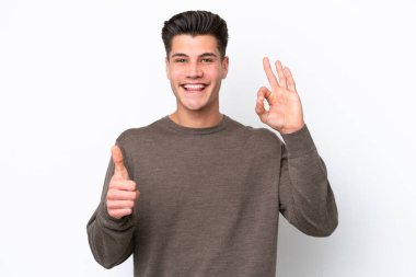 Beyaz bakkalda izole edilmiş yakışıklı beyaz bir adam işaret veriyor ve el hareketi yapıyor.