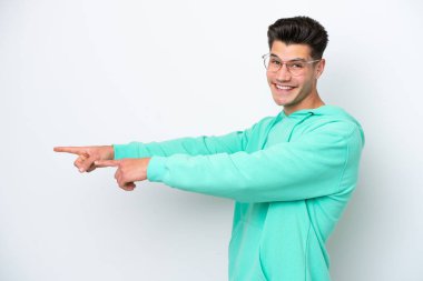 Beyaz bakkalda izole edilmiş genç, yakışıklı beyaz bir adam. Parmakla göstererek bir ürün sunuyor.