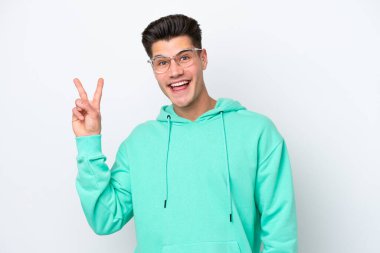 Beyaz fırında izole edilmiş yakışıklı beyaz adam gülümsüyor ve zafer işareti gösteriyor.