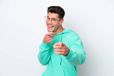 Beyaz fırında izole edilmiş genç, yakışıklı beyaz bir adam ön tarafı işaret ediyor ve gülümsüyor.