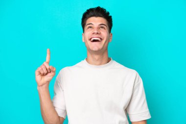 Genç, yakışıklı, beyaz bir adam, mavi fırında izole edilmiş, yukarı bakıyor ve şaşırıyor.