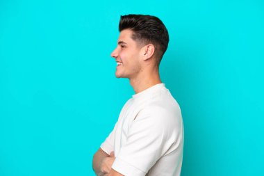 Genç, yakışıklı, beyaz bir adam, mavi fırında tek başına, yan pozisyonda.