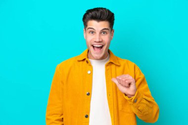 Genç, yakışıklı, beyaz bir adam mavi fırında izole edilmiş ve yüzünde sürpriz bir ifade var.