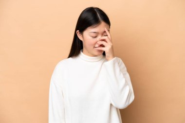 Young Chinese woman isolated on beige background laughing