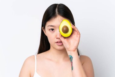 Beyaz arka planda avakado tutan genç Çinli bir kadın. Portreyi kapat