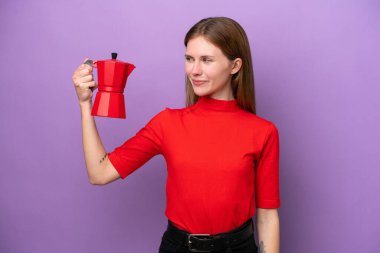 Young English woman holding coffee pot isolated on purple background with happy expression