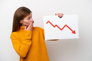 Young English woman isolated on white background holding a sign with a decreasing statistics arrow symbol with surprised expression