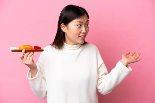 Young Chinese Woman Holding Sashimi Isolated Pink Background Surprise Expression — стоковое фото