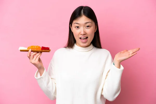 Young Chinese Woman Holding Sashimi Isolated Pink Background Shocked Facial — стоковое фото