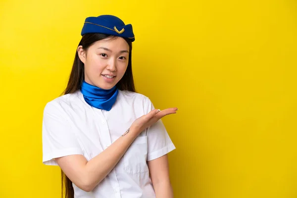 飞机上被黄色背景隔离的中国妇女空姐带着一种想法 面带微笑地看着前方 — 图库照片
