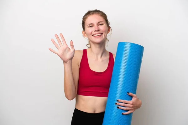 年轻的英国女子参加瑜伽课 手里拿着一块被白色背景隔开的垫子 用手指数着5 — 图库照片
