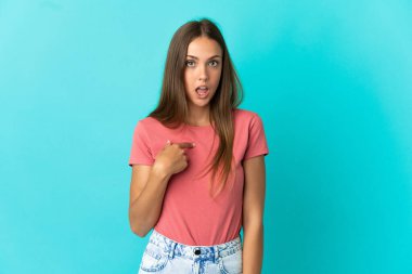 İzole edilmiş mavi arka planı olan genç bir kadın kendini işaret ediyor.